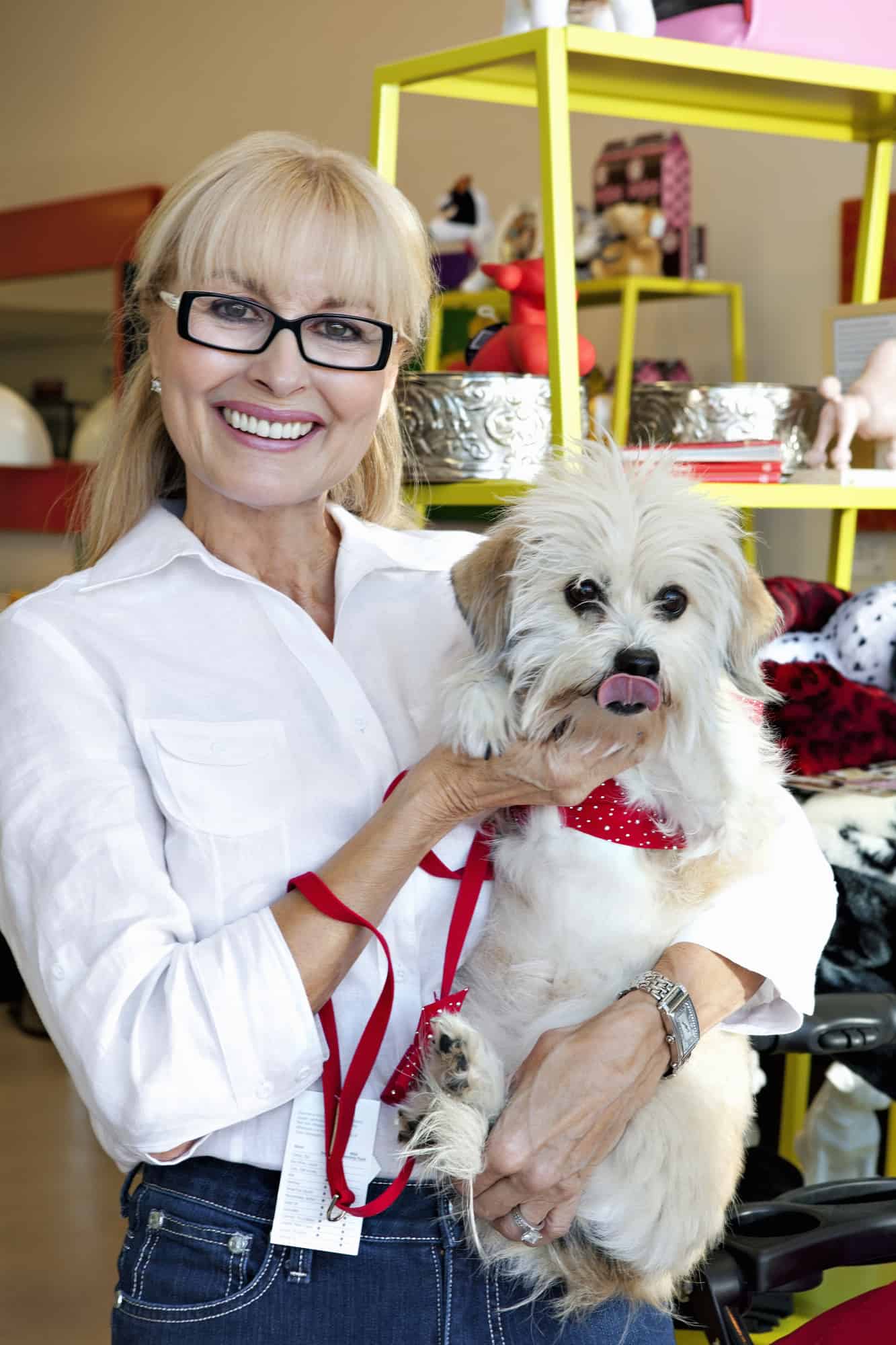 A woman in a white shirt holds a small white dog